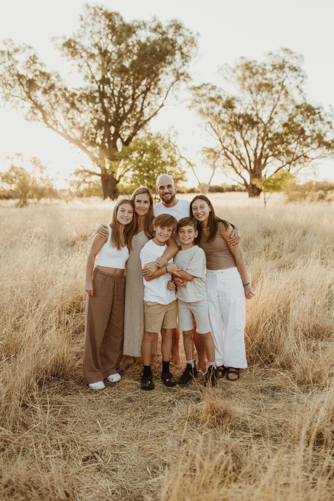Alex Dennis with his wife and four children in a Perth bush paddock at sunset