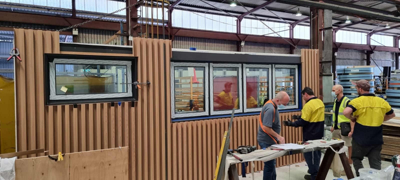 Alex Dennis with the factory team as the timber-clad walls of the Padbury home are assembled