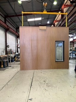 Timber-clad wall panel with window on a factory hoist