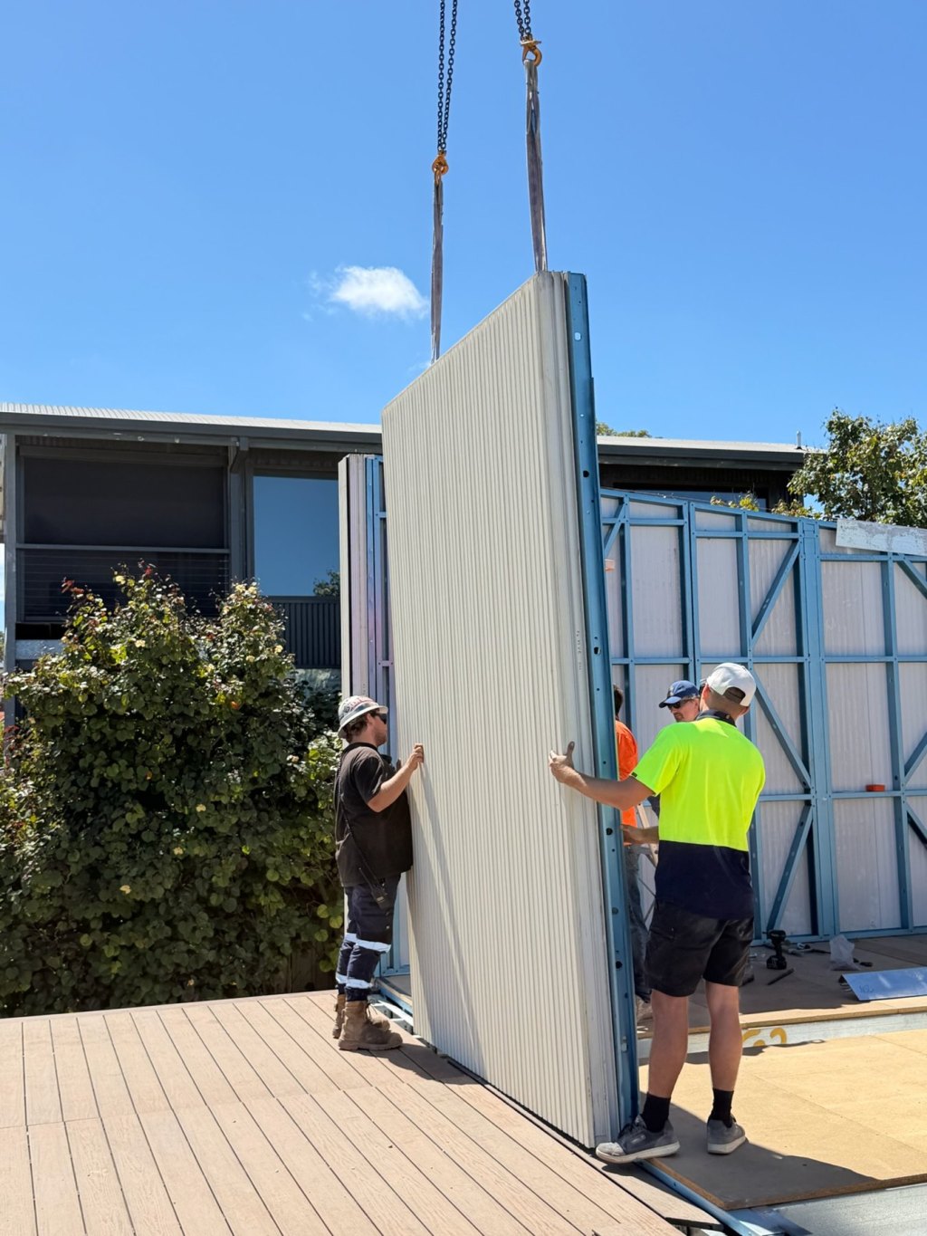 Installers guiding an insulated wall panel off a crane onto a prototype home